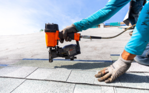Roofing installer fastening asphalt shingles during a roof replacement